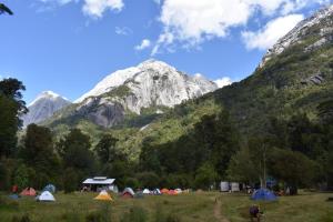 un grupo de tiendas de campaña en un campo con montañas en el fondo en Cabañas Chucao Austral, en Puerto Montt