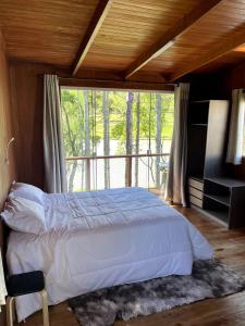 a bedroom with a bed and a large window at Pousada Lago do Amanhecer in Capão Alto
