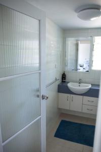 a white bathroom with a sink and a mirror at Beach Haven in Mission Beach
