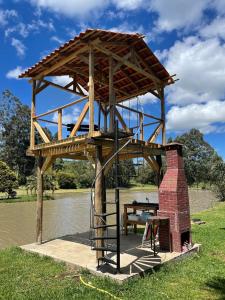 een houten paviljoen met een picknicktafel aan het water bij Pousada Lago do Amanhecer in Capão Alto