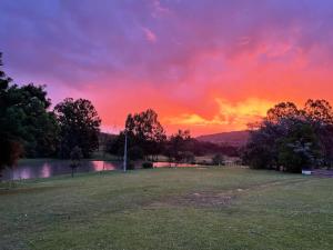 a sunset in a park with a field and trees at Pousada Lago do Amanhecer in Capão Alto