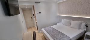1 dormitorio con 1 cama blanca y TV en CH La Petite Maison - Boutique - Madrid, en Madrid