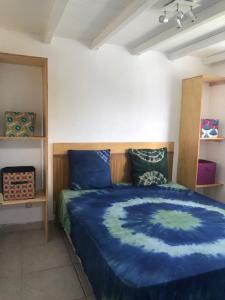 a bedroom with a bed with a blue comforter at Les Chambres d'Umoja in Grand-Bourg