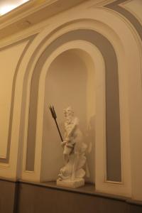 Una statua di un uomo che tiene una bacchetta su uno scaffale. di B&B Scarlatti 60 a Napoli