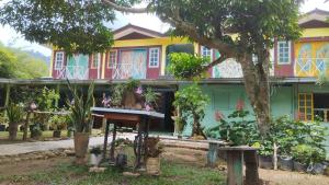 uma casa colorida com uma árvore em frente em Fatehah Inn em Kuala Tahan