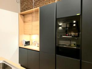 een keuken met een zwarte koelkast en een wastafel bij Brand new ROOMS with private bathroom and balcony-terrasse in Brussel