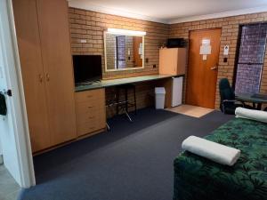 a room with a bed and a desk with a computer at Macintyre Motor Inn in Goondiwindi