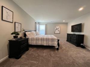 ein Schlafzimmer mit einem Bett, einer Kommode und einem TV in der Unterkunft 7876 Ellington Court Cheerful 4 Bedroom Home Brand New Construction in Maineville