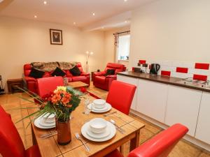 a kitchen and living room with a table and red chairs at Cow Byre in Little Tew