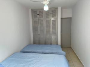 een slaapkamer met 2 bedden en een plafondventilator bij Apartamento 2 Guarujá enseada 2 dorm, 200m praia Ed Carpentier in Guarujá