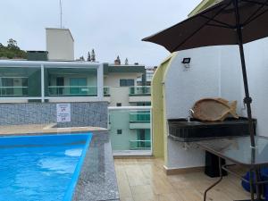 una piscina con una sombrilla y un lavabo en el balcón en Ilha de Molokini Centro Bombinhas -SC, en Bombinhas