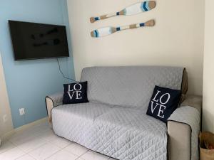 sala de estar con sofá gris y TV de pantalla plana en Ilha de Molokini Centro Bombinhas -SC, en Bombinhas