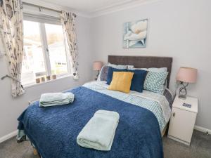 a bedroom with a blue bed with two towels on it at The Retreat in Narberth