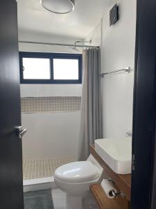 a bathroom with a white toilet and a sink at Casa Daniel in Ensenada