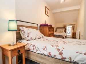ein Schlafzimmer mit einem Bett und einem Tisch mit einer Lampe in der Unterkunft The Stables in Chipping Norton