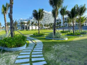 a walkway in a park with palm trees and a building at Seaview Arena Cam Ranh Nha Trang hotel near the airport in Cam Ranh