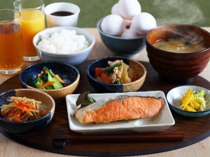 una mesa de madera con tazones de comida y un plato de pescado en Henn na Hotel Express Nagoya Fushimi Ekimae en Nagoya