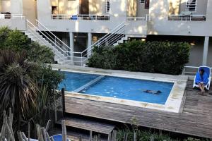 una mujer sentada en una silla junto a una piscina en Las cañas Pinamar - Duplex 3 ambientes en Pinamar