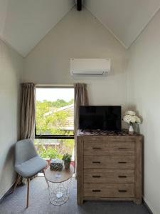 uma sala de estar com uma televisão, uma cómoda e uma janela em Charm on Chippendale B&B em Palmerston North