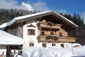 uma casa coberta de neve com uma montanha ao fundo em Ferienhaus Niedermoser em Leogang