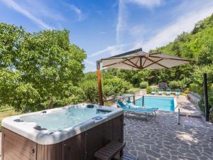 bañera de hidromasaje con sombrilla junto a la piscina en Belvilla by OYO Villa Artisti, en Piobbico