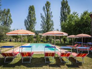 um grupo de cadeiras e guarda-sóis ao lado de uma piscina em Belvilla by OYO Villa Sapori em Pergola