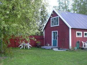eine rote Scheune mit einem Picknicktisch im Hof in der Unterkunft Ringbomsvägen Holiday Home in Ljugarn