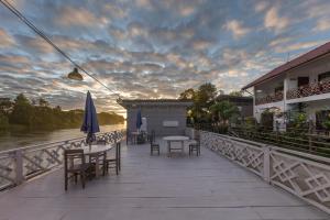 eine Terrasse mit Tischen und Sonnenschirmen auf einer Brücke in der Unterkunft BABA Guesthouse in Don Det