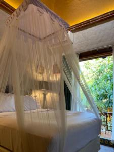 um quarto com uma cama de dossel e uma janela em ETNICO LOCAL HOUSE em Chiconcuac