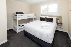 a white bedroom with a white bed and a window at BIG4 River Myall Holiday Resort in Bulahdelah +30 photos