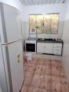 uma cozinha com um frigorífico branco e piso em madeira em Casa Natureza, Mar, Floresta e Tranquilidade em Ubatuba