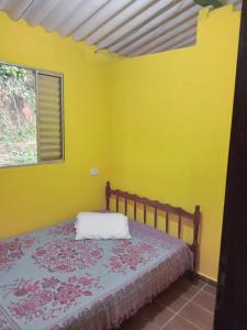 um quarto com uma cama com paredes amarelas e uma janela em Casa Natureza, Mar, Floresta e Tranquilidade em Ubatuba
