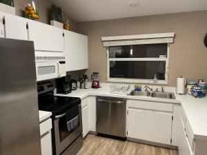 cocina con armarios blancos, fregadero y microondas en Cozy 3 bedrooms home close to everything in Tampa! en Tampa