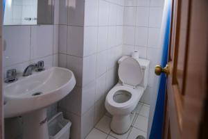 Łazienka z białą toaletą i umywalką w obiekcie Pacha Hostel w mieście Puno
