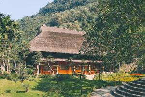 una casa con techo de paja y escalera en Thung Nham Resort en Ninh Binh