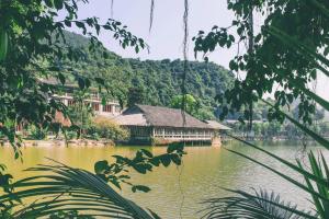 een huis aan een meer met een berg op de achtergrond bij Thung Nham Resort in Ninh Binh