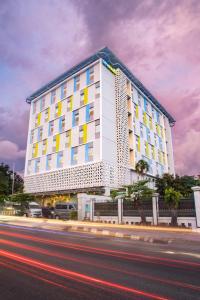 a large white building with yellow windows on a street at Hotel Citradream Tugu Yogyakarta in Yogyakarta