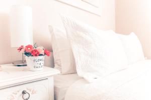 uma cama branca com um vaso de flores numa mesa de cabeceira em Hostal Pehuenche em Talca