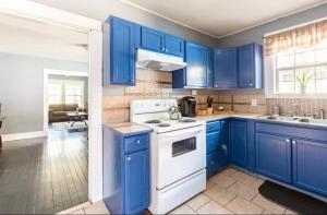 a kitchen with blue cabinets and a white stove top oven at Cozy Yellow Home near LSU and Downtown in Baton Rouge