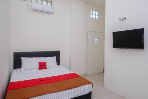 a bedroom with a bed with a television on a wall at RedDoorz near Alun Alun Magelang 2 in Magelang