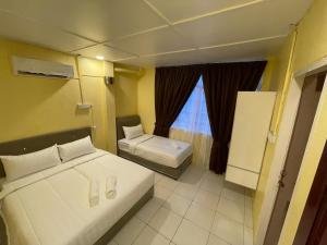 a small bedroom with two beds and a window at Hotel Sri Maju Jaya in Kota Bharu