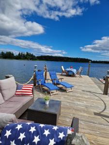 a dock with chairs and a couch on the water at Timber house with private beach and boat including. in Njurundabommen