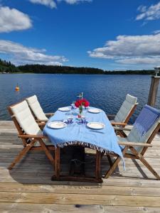 una mesa con un paño de mesa azul y sillas en un muelle en Timber house with private beach and boat including. en Njurundabommen