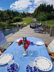 een tafel met blauwe en witte borden en bloemen erop bij Timber house with private beach and boat including. in Njurundabommen