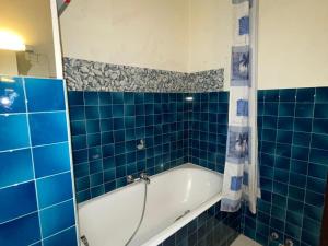 ein blau gefliestes Bad mit einer Badewanne. in der Unterkunft Studio Châtel, 1 pièce, 4 personnes - FR-1-693-67 in Châtel