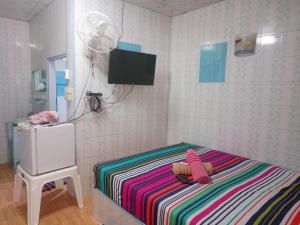 Dormitorio pequeño con cama y TV en la pared en Kanjana Resort, en Suratthani