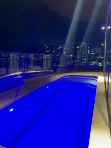 - une piscine bleue sur le toit d'un bâtiment la nuit dans l'établissement Central Canberra City apartment with study and full amenities including parking, à Canberra