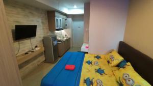 una piccola camera da letto con un letto blu con una coperta gialla di Mushroom Apartment Grand Kamala Lagoon by Mrs Sewa a Pekayon Satu