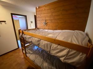 a large bed in a room with a wooden wall at Appartement La Chapelle-d'Abondance, 2 pièces, 6 personnes - FR-1-692-23 in La Chapelle-dʼAbondance