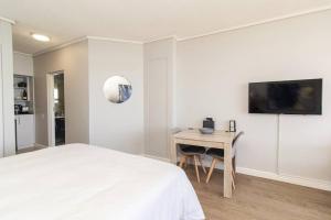 a bedroom with a bed and a desk and a tv at Luxury Studio with a View in Summerstrand